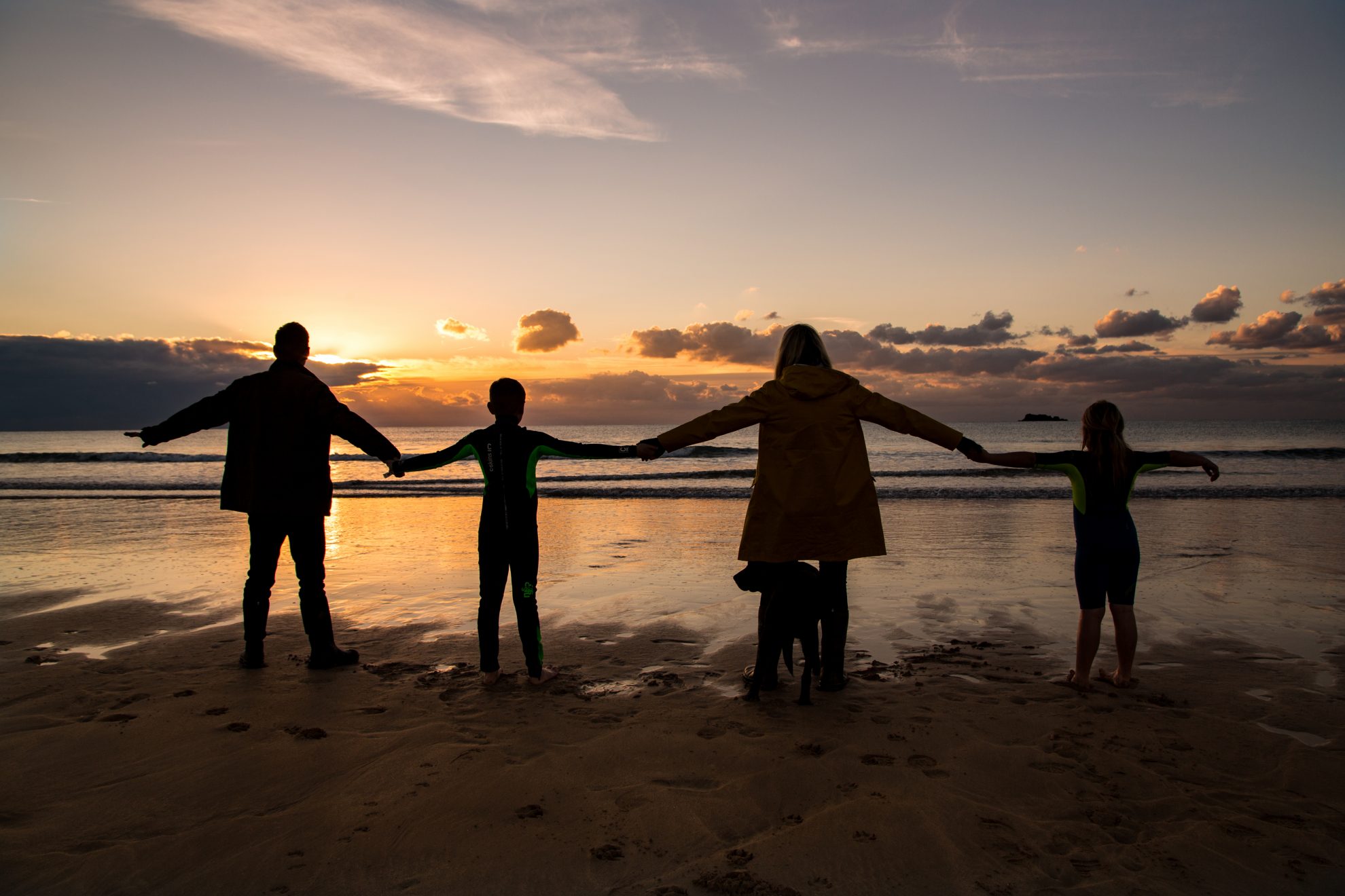 Family holding hands on the beach at Booby's Bay, near Padstow for a family photoshoot at sunset